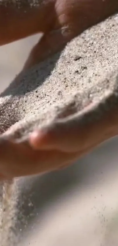 Close-up of a hand letting fine sand flow gently, creating a calming visual.