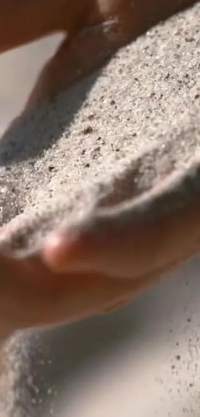 Close-up of hands holding soft, light brown sand.