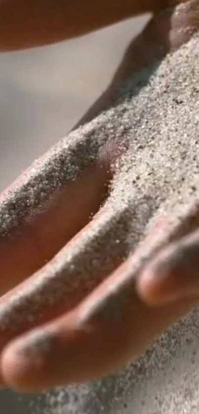 Close-up of hand covered in fine sand, showcasing serene natural beauty.