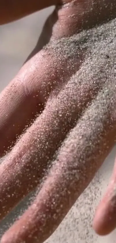 Close-up of a hand sprinkled with fine sand, creating a serene background.