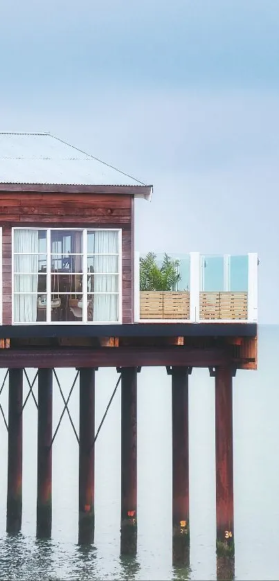 Serene cabin on pier above calm sea with blue sky background.