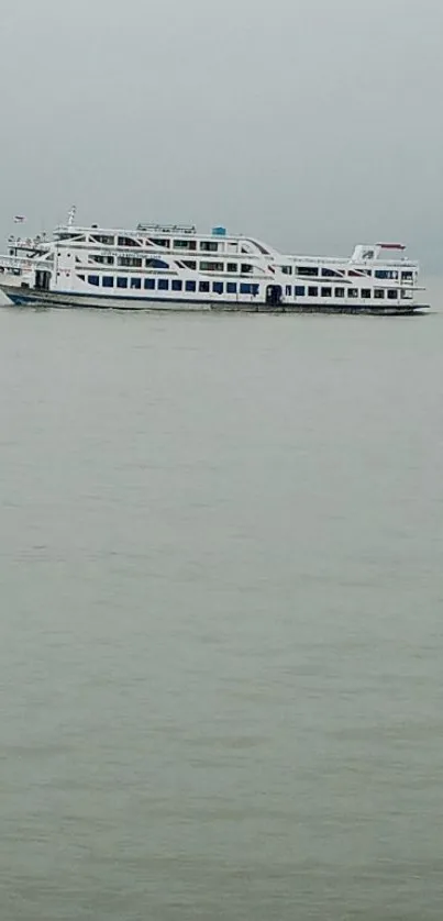 A boat sails in calm sea under an overcast sky.