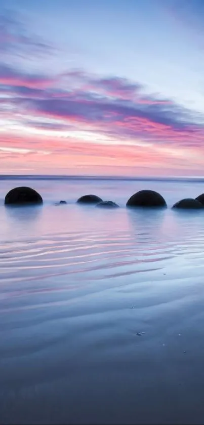 Serene beach scene with pink sunset and spherical rocks on the shore.