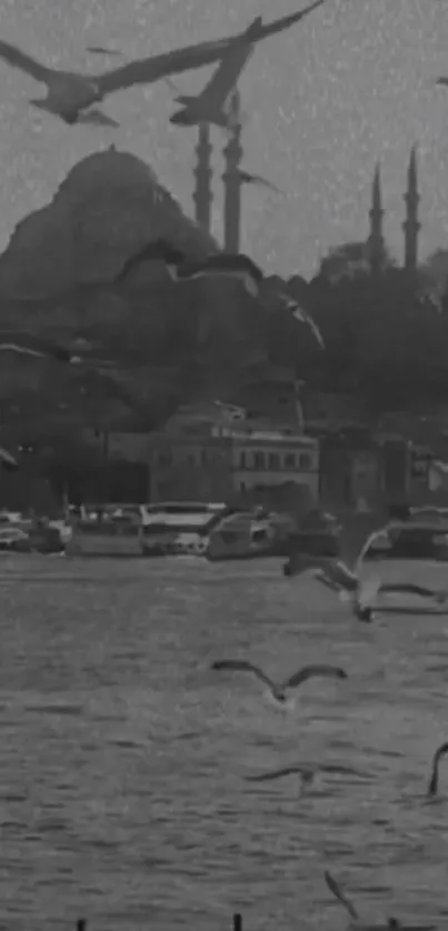 Black and white wallpaper of birds flying over a seaside with distant buildings.