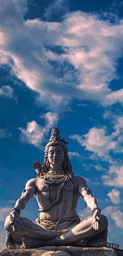 Lord Shiva sculpture under a cloudy blue sky.