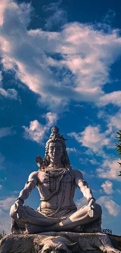 Majestic Lord Shiva statue under a blue sky with clouds.