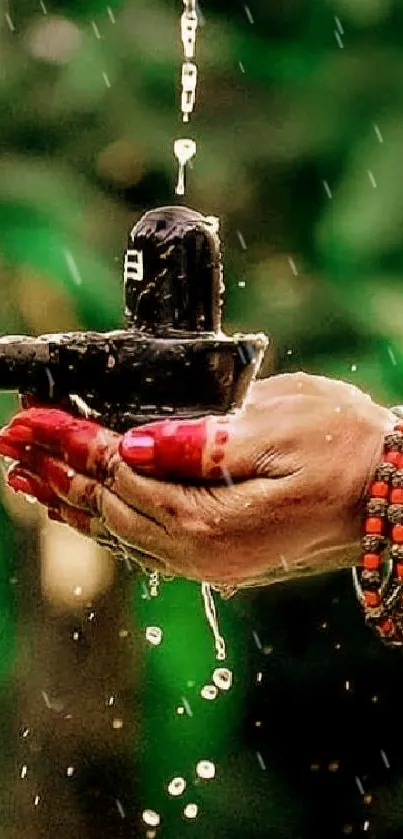 A hand holding a Shivling with water and beads, against a green background.