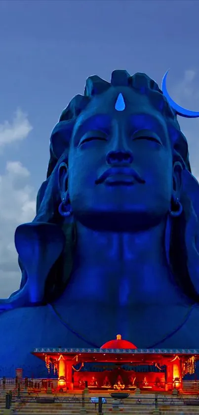 Majestic blue Shiva statue with clouds in the background.