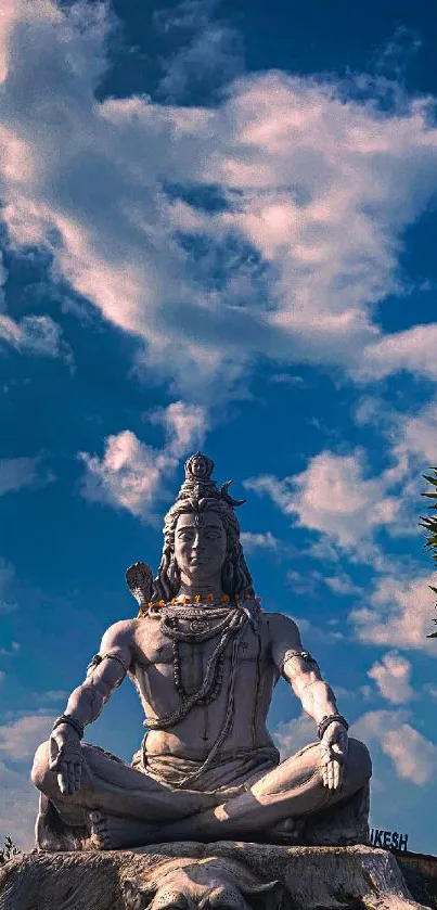 Majestic Shiva statue under a vivid blue sky with fluffy clouds.