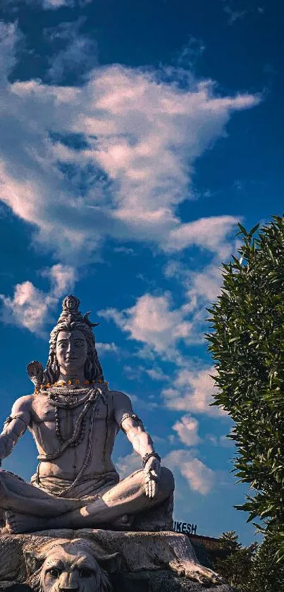 Shiva statue with blue sky background and fluffy clouds.