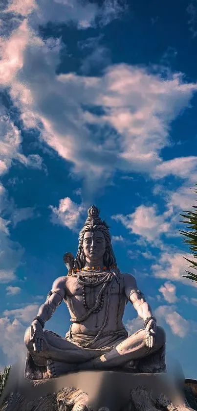 Shiva statue under a blue sky with clouds.