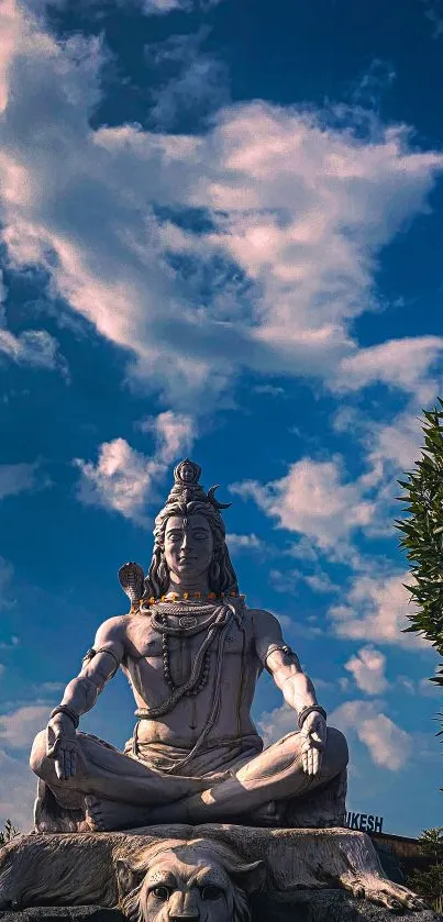 Majestic Shiva statue under a blue, cloud-filled sky.