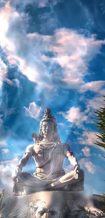 Shiva statue against a blue and cloudy sky in peaceful meditation.