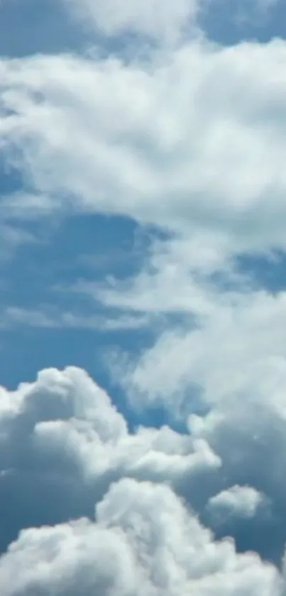 Fluffy white clouds in a bright blue sky wallpaper.