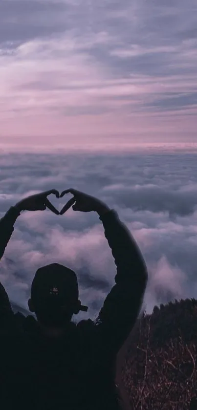 Silhouette and heart shape against pink sky and clouds on mobile wallpaper.