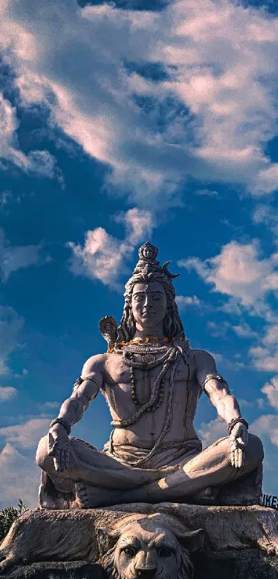 Mobile wallpaper of Shiva statue against a blue sky with clouds and trees.