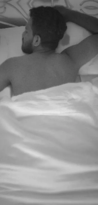 Black and white image of a person sleeping peacefully on white sheets.