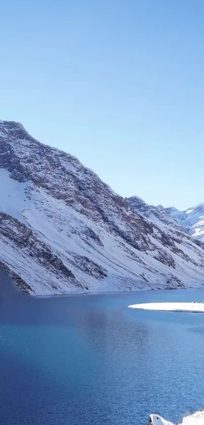 Snowy mountain overlooking a tranquil blue lake.