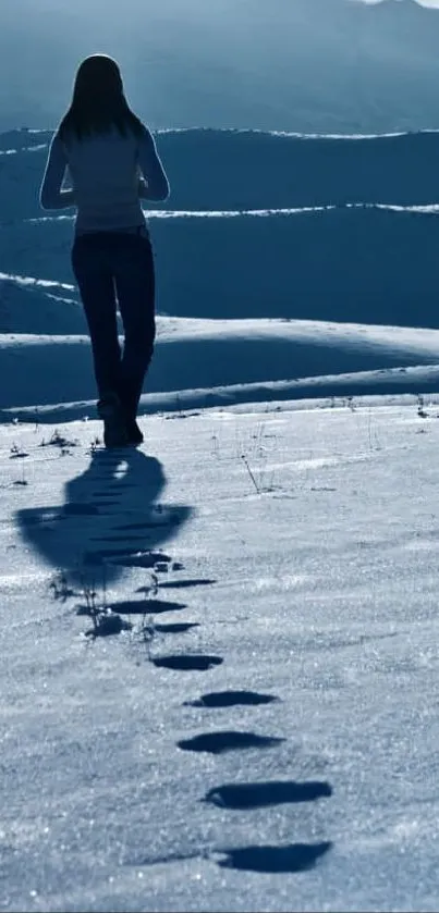 A lone figure walks through snowy mountains under a clear blue sky.