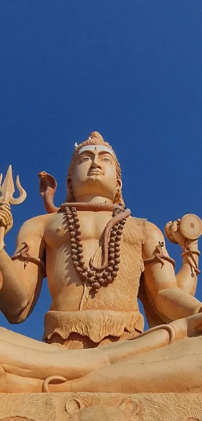 Majestic deity statue under a blue sky with serene ambiance.