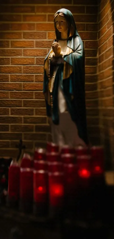 Statue surrounded by glowing candles against a brick wall.