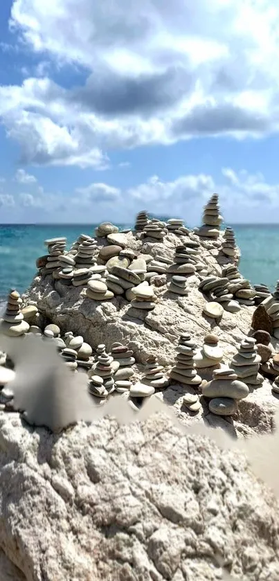 Stacked stones on a serene beach with a clear blue sky and ocean.