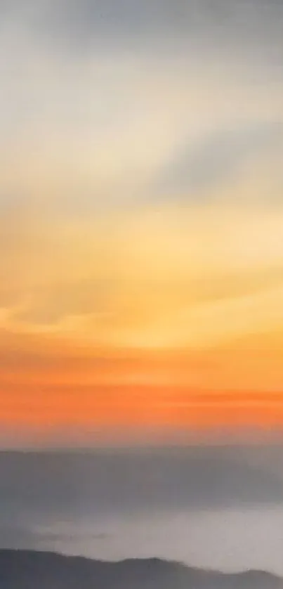 Serene sunrise over misty mountains in orange hues.
