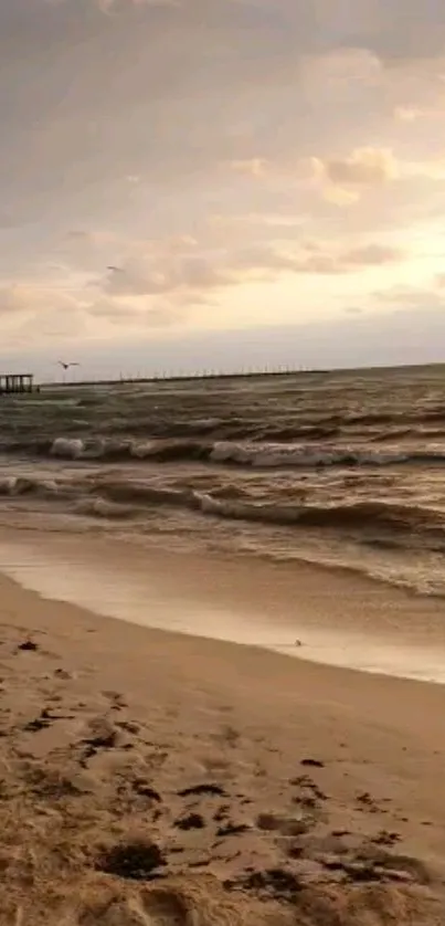 Calm beach at sunset with waves and cloudy sky.