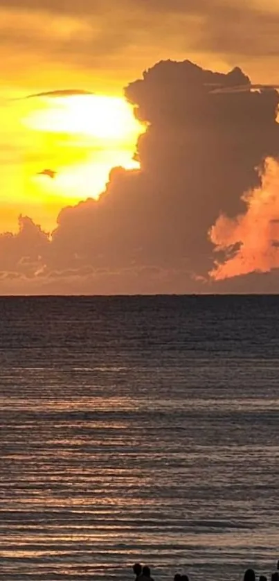 Golden sunset over a tranquil ocean with silhouettes on the beach.