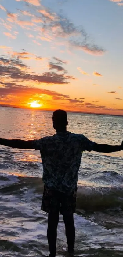 Silhouette on a beach at sunset over the ocean with a colorful sky.