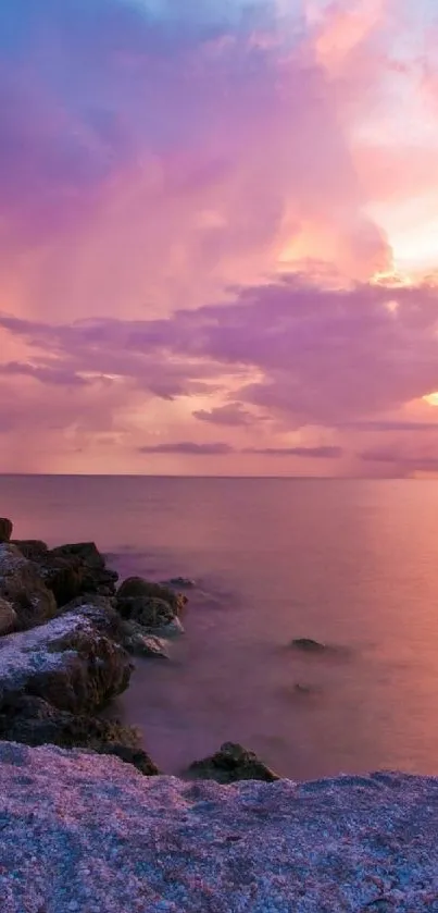 Beautiful sunset over a rocky beach with purple and orange hues in the sky.