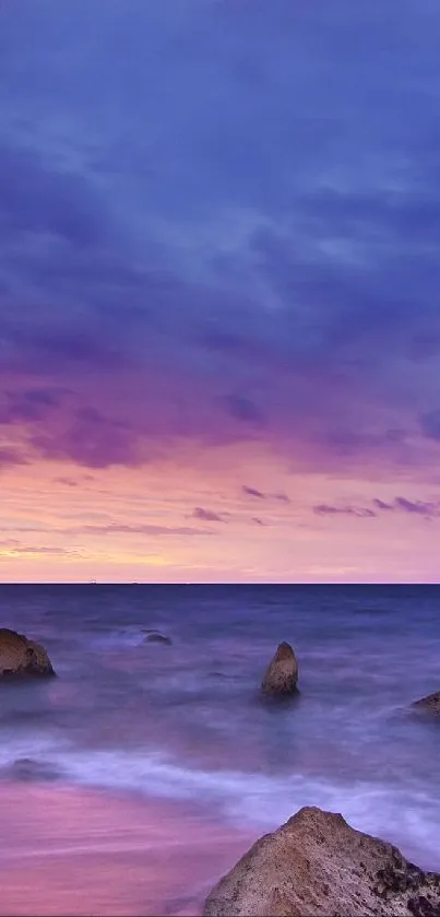 Serene beach at sunset with purple sky and ocean waves.