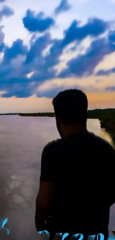 Silhouette by river at sunset with a dramatic sky.