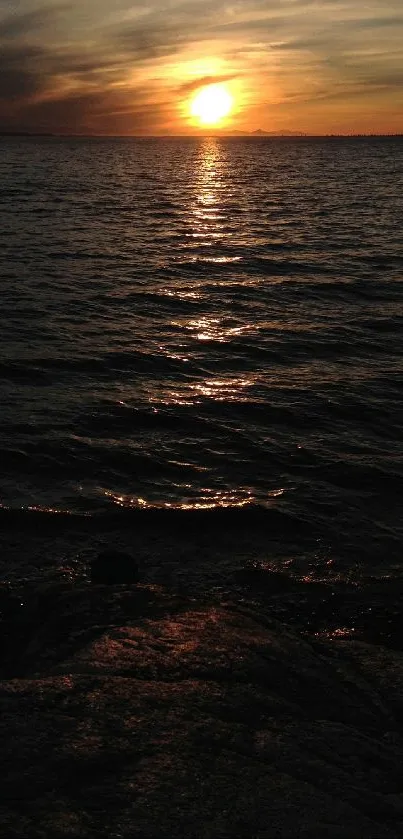 Sunset over ocean with dark waters and bright horizon.