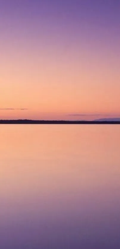 Serene sunset over a calm purple lake with an orange sky.