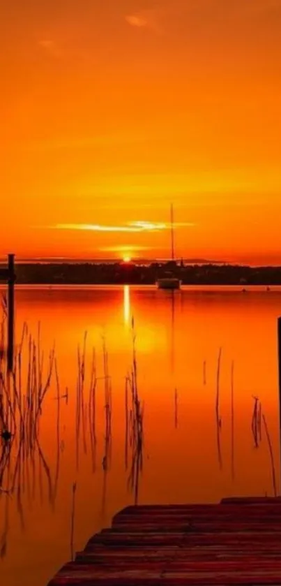 Serene sunrise over calm orange waters with silhouetted boat and dock.