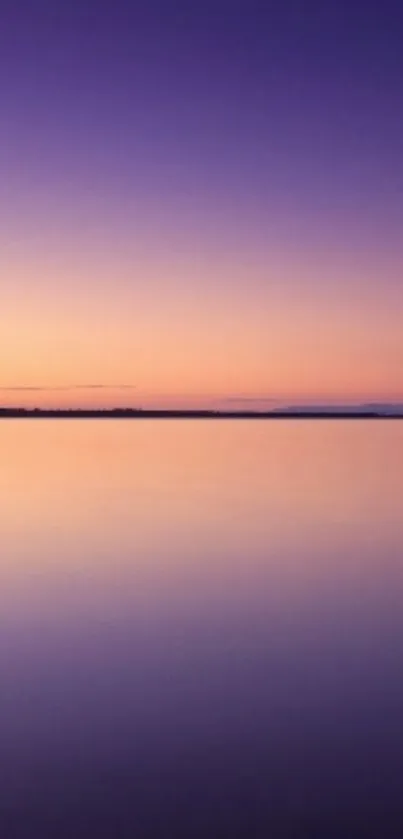 Serene lake at sunset with purple and orange sky.