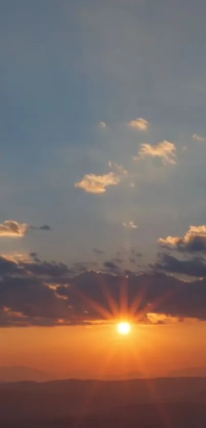 Sunset over mountains with vibrant sky hues and scattered clouds.