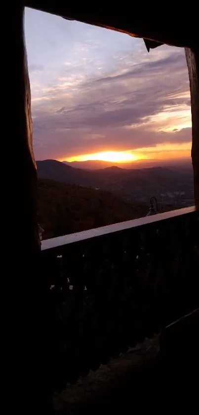 Sunset over mountains seen through a wooden window, creating a serene view.