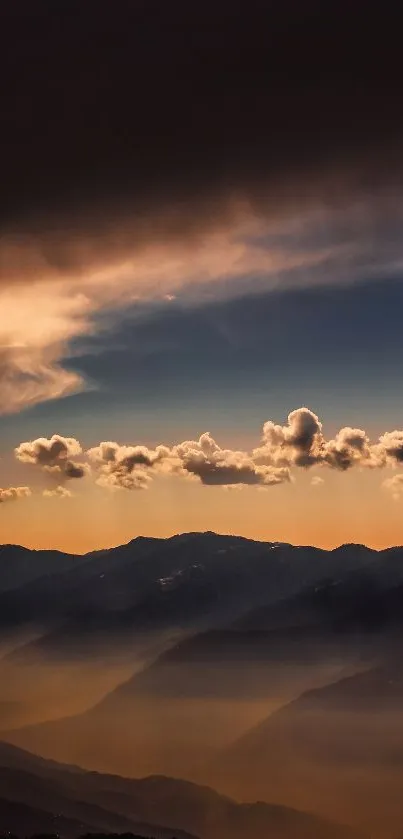 Serene sunset over misty mountains with clouds and orange-blue sky.