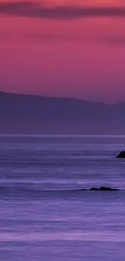 Purple sunset over a calm ocean with soft clouds.