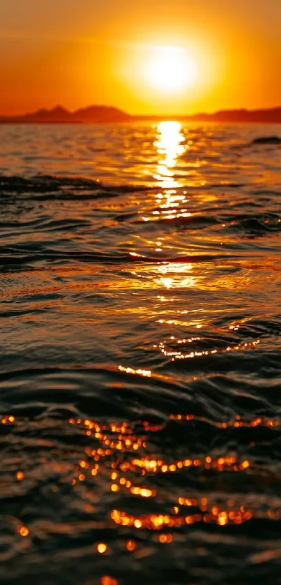 Vibrant orange sunset reflecting on a calm ocean surface.