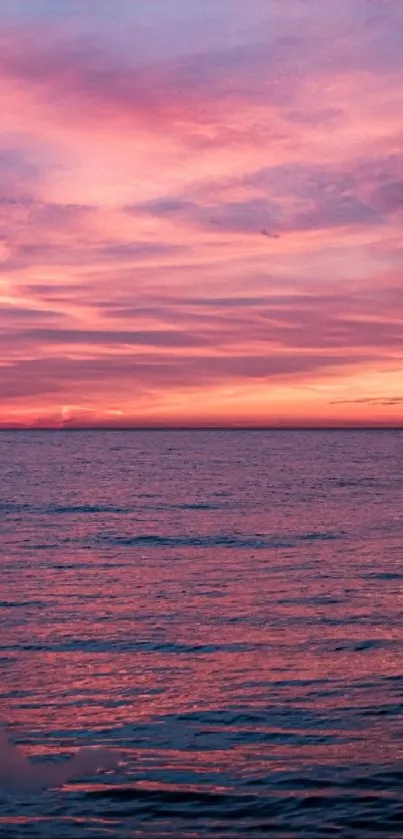 Serene sunset over the ocean with pink sky reflection.