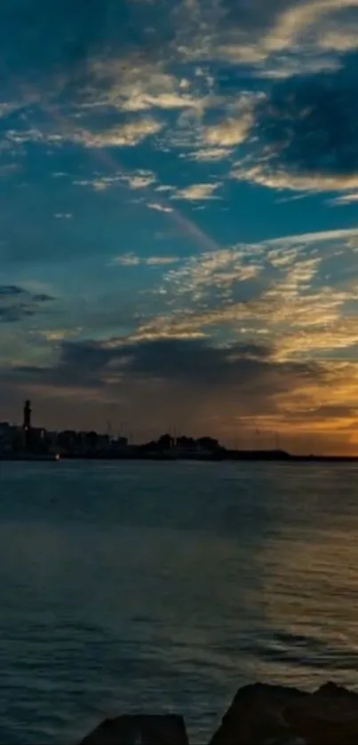 Sunset over calm waters with distant city silhouette and colorful sky.