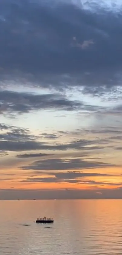 Sunset over calm ocean under a colorful cloudy sky.