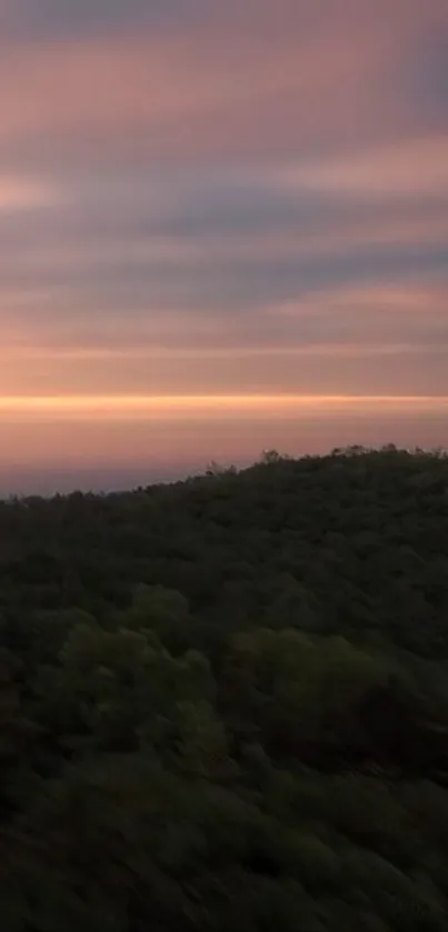 Beautiful sunset over lush green hills with a soft pink sky.