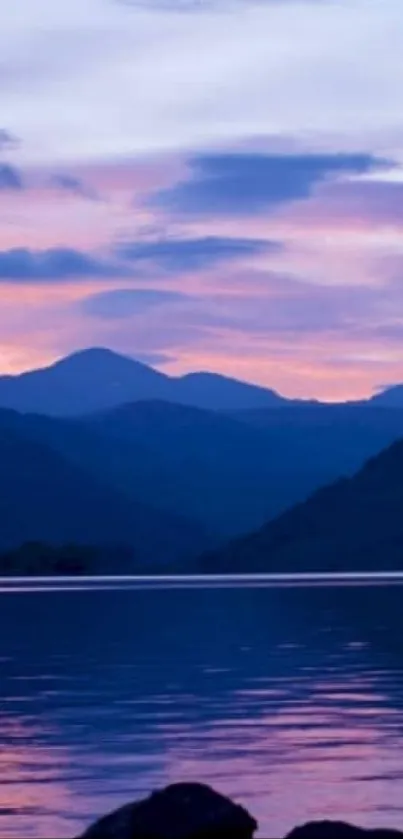 Serene sunset over a mountain lake with pastel sky reflections.