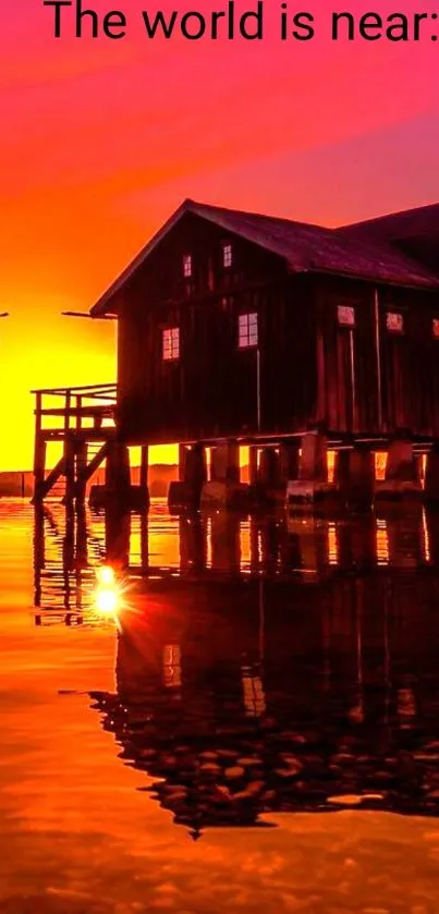 Tranquil sunset over a lakeside cabin with vibrant orange and pink sky.