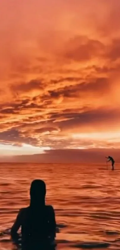 Silhouette in orange sunset over ocean with serene sky.