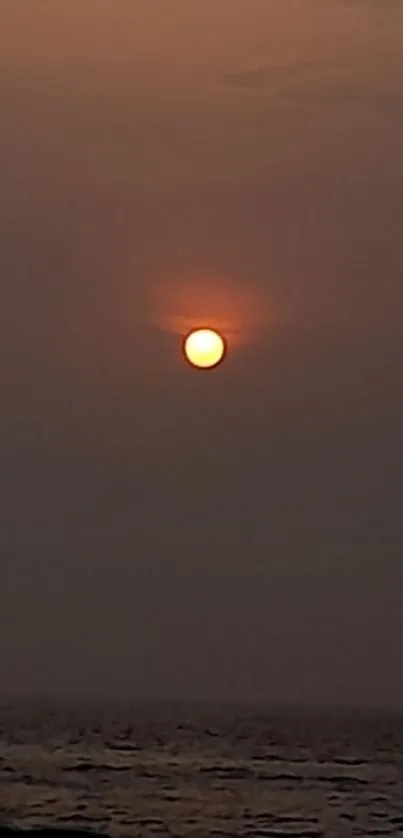 A tranquil sunset over a calm ocean with an orange sky.